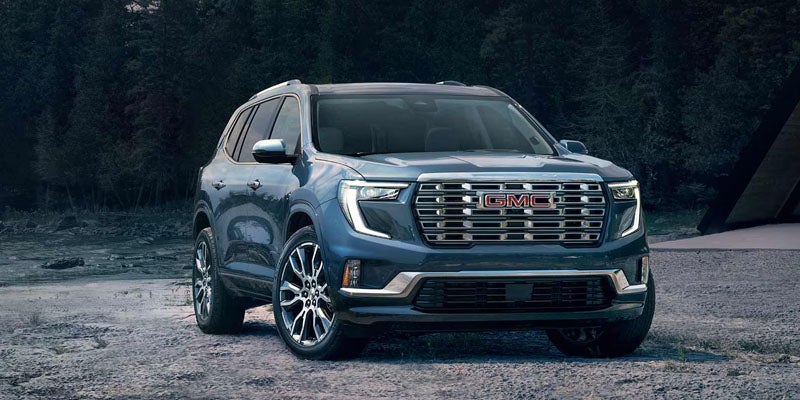 Blue 2026 GMC Acadia parked by trees.