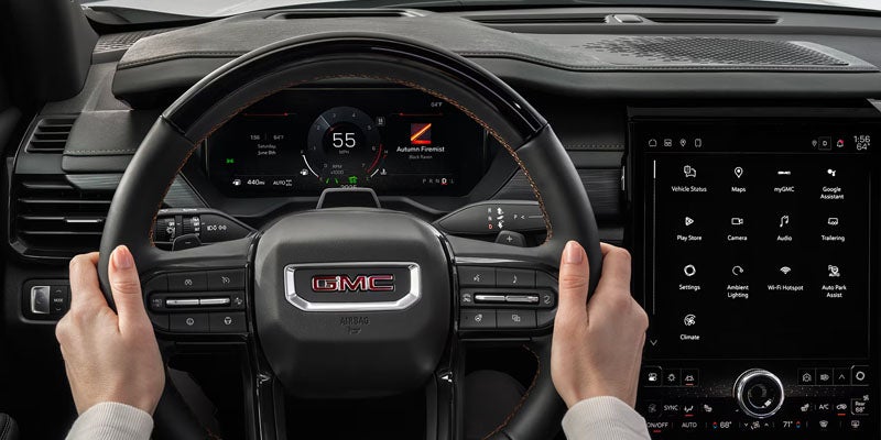 Hands holding steering wheel in a GMC Acadia.