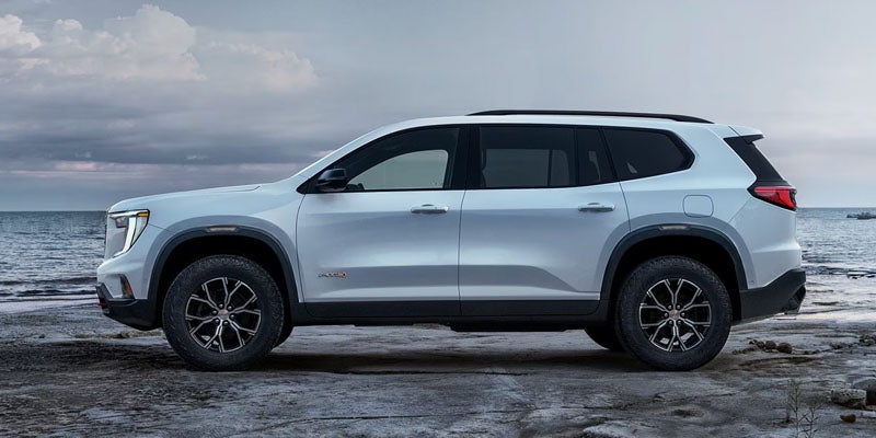 White 2026 GMC Acadia side view at beach.