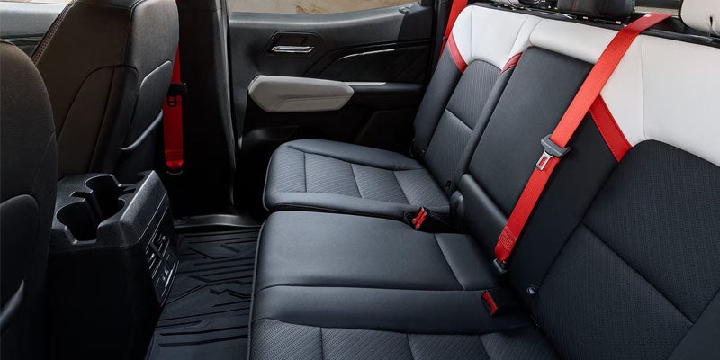 Rear seats of a 2026 GMC Canyon with red seatbelts.