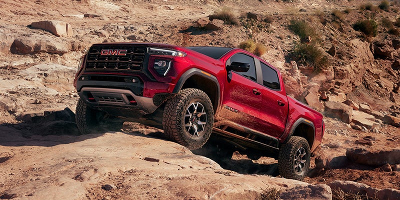 Red 2026 GMC Canyon climbing steep rocks.